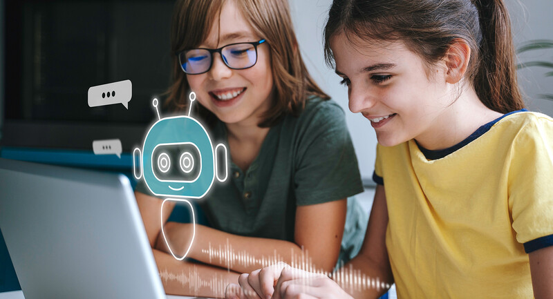 Two students smile as they interact with an AI chatbot on a computer screen